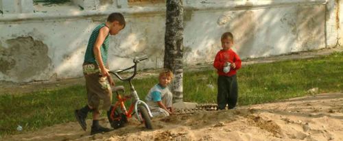 Children play in fresh sand after heavily lead-contaminated soil has been removed.